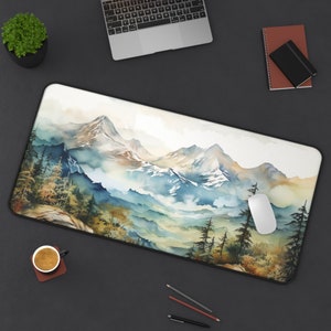 May include: A watercolour-style mouse mat featuring a mountain range with a blue, green and white colour scheme. The mouse mat has a black border and is designed to be used with a computer mouse.