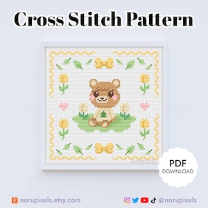 May include: Cross stitch pattern featuring a brown bear with a pink nose and a green tree in its paws. The bear is surrounded by yellow tulips, green leaves, and yellow bows. The pattern is framed in a white frame with a yellow border.