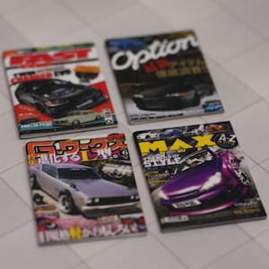 May include: Four Japanese car magazines with different covers featuring photos of modified cars. The covers are titled "East", "Option", "G-Works", and "Max".