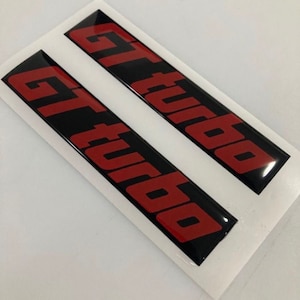 May include: Two black and red "GT Turbo" decals. The decals are glossy and have a 3D effect.