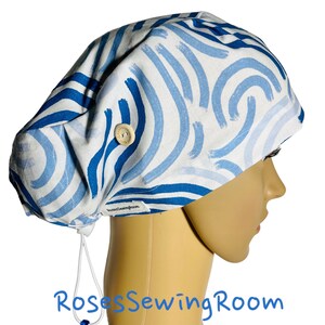 May include: A blue and white patterned scrub hat with a button on the side and a drawstring. The hat is made of fabric and has a soft, comfortable feel. The hat is ideal for nurses, doctors, and other healthcare professionals.
