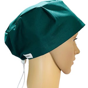 May include: A dark green scrub cap with a white drawstring. The cap is made of a soft, comfortable fabric and has a simple, practical design.