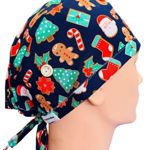 May include: A blue scrub hat with a Christmas-themed print featuring gingerbread men, candy canes, Christmas trees, and Santa Claus. The hat has a button on the top and ties at the back.