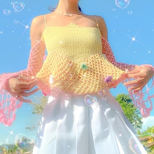 May include: A yellow and pink crochet top with a loose fit and wide sleeves. The top has a delicate, lacy pattern and is perfect for a summer day.