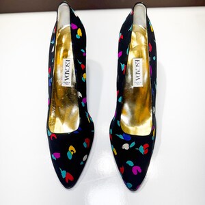 Puede incluir: Un par de zapatos de tac&oacute;n Escada negros con un estampado de confeti colorido. Los tacones tienen una punta afilada y una plantilla dorada. La etiqueta Escada es visible en el interior de cada zapato.