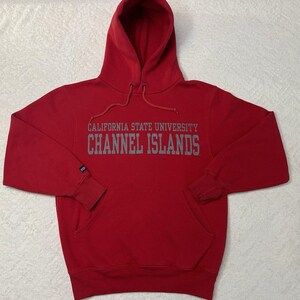 Puede incluir: Sudadera roja con capucha con el texto "California State University Channel Islands" en letras grises.