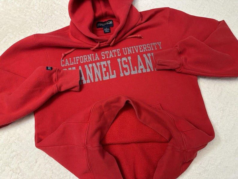 Puede incluir: Sudadera roja con capucha con el texto "California State University Channel Islands" en letras grises.