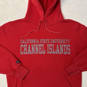 Puede incluir: Sudadera roja con capucha con el texto "California State University Channel Islands" en letras grises.