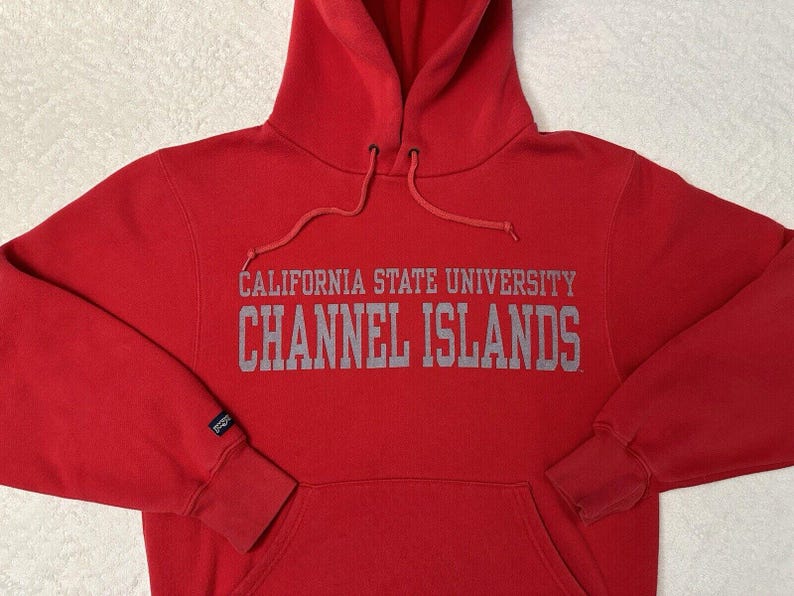 Puede incluir: Sudadera roja con capucha con el texto "California State University Channel Islands" en letras grises.