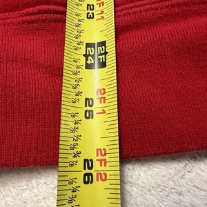 Puede incluir: Primer plano de una tela roja medida con una cinta m&eacute;trica amarilla. La cinta m&eacute;trica muestra 2 pies 6 pulgadas.