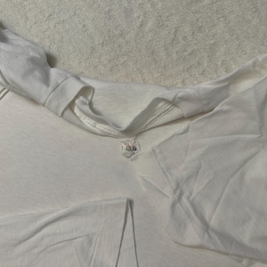 Peut inclure: Un t-shirt blanc avec un col rond et des manches courtes. Le t-shirt est fait d'un tissu doux et léger. L'étiquette est visible au dos du cou. Le t-shirt est plié.