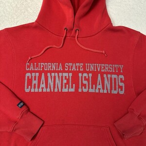 Puede incluir: Sudadera roja con capucha con el texto "CALIFORNIA STATE UNIVERSITY CHANNEL ISLANDS" en letras grises.