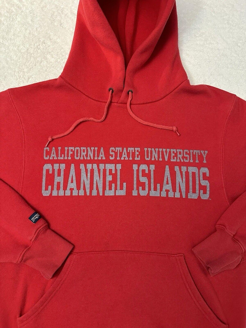 Puede incluir: Sudadera roja con capucha con el texto "CALIFORNIA STATE UNIVERSITY CHANNEL ISLANDS" en letras grises.