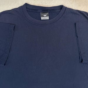 May include: A navy blue t-shirt with a crew neck. The shirt has short sleeves and a tag that reads "Cheetah". The shirt is made of a soft material, likely cotton.