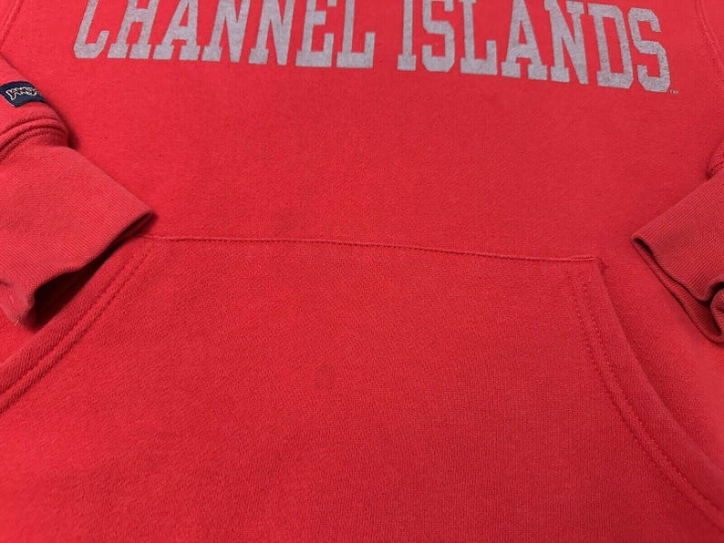 Puede incluir: Sudadera roja con capucha con un logotipo gris "CHANNEL ISLANDS" impreso en la parte delantera.