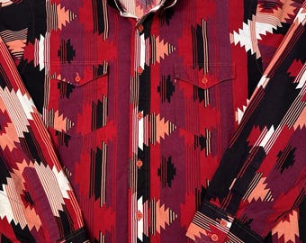 Könnte beinhalten: Ein langärmliges Hemd mit Knöpfen und einem geometrischen Muster in Rot, Schwarz und Weiß. Das Hemd hat ein Wrangler-Markenetikett auf der linken Brust.