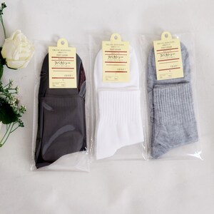 May include: Three pairs of socks in black, white, and gray. The socks are packaged in clear plastic bags with a label that reads "Foot Cover" in Japanese and English.