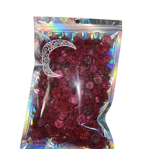 May include: A clear plastic bag filled with dried red and purple flowers and berries. The bag has a holographic iridescent finish.
