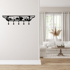 Puede incluir: Perchero de pared de metal negro con una escena de granja que presenta un granero, montañas y animales. El perchero tiene cinco ganchos.