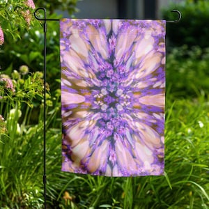 May include: A purple and white garden flag with a floral design. The design is symmetrical and features a central cluster of purple flowers surrounded by white petals.
