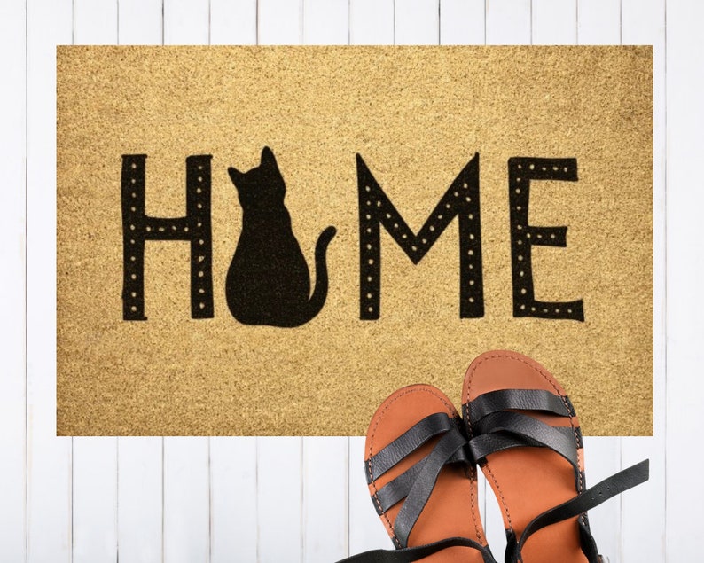 May include: A brown doormat with the word "HOME" in black lettering with a black silhouette of a cat sitting in the middle of the word.