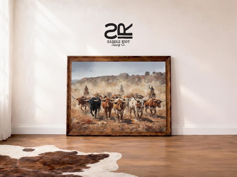 a framed painting of a group of cattle on a dirt road, with a cowboy on horseback leading the herd.