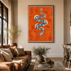 May include: A framed wall art print featuring a vertical, S-shaped blue snake with a white floral pattern against a solid, textured orange background. The snake has a light yellow outline, and the artwork is displayed in a dark brown frame.