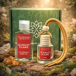May include: A car air freshener set with a refill oil bottle and a hanging diffuser. Both bottles have red labels with the text "SCARLET FLAME" and "The Blooming Cactus & Co." The hanging diffuser has a yellow cord. A green box with cactus illustrations is in the background.