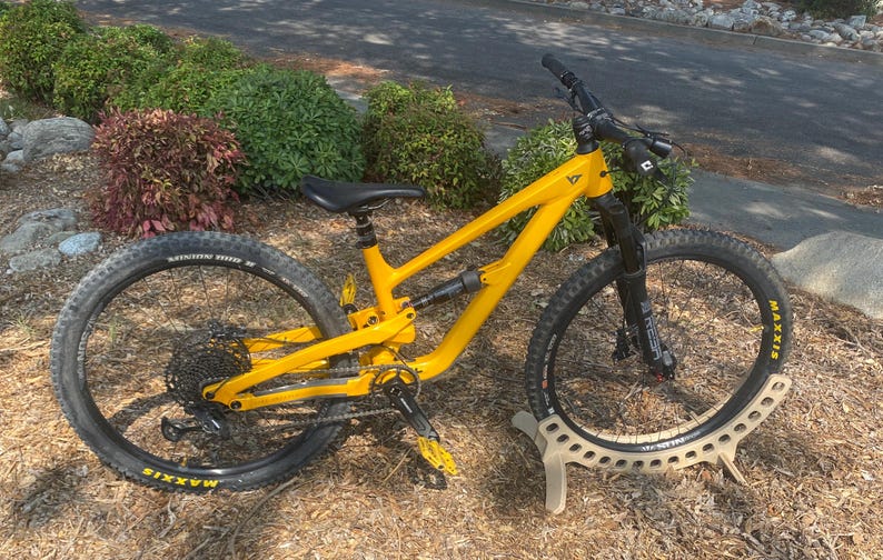 Birch plywood bike stand with a sleek, curved design. This minimalist stand securely supports your bike, blending function with style – perfect for homes, garages, or shops. Durable, modern, and eye-catching.