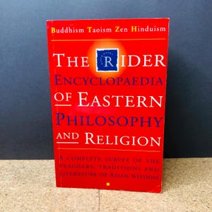 May include: A red hardcover book, "The Rider Encyclopaedia of Eastern Philosophy and Religion." The title is in white and blue text. The book's cover also includes the words "Buddhism Taoism Zen Hinduism" at the top, and a brief description at the bottom.