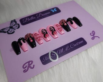 May include: A set of ten press-on nails in a coffin shape, featuring a mix of solid black and light pink colors. Some nails display a ghost-like character graphic, pink text reading "WHAT'S YOUR HARRY UP", and pink rhinestone embellishments.