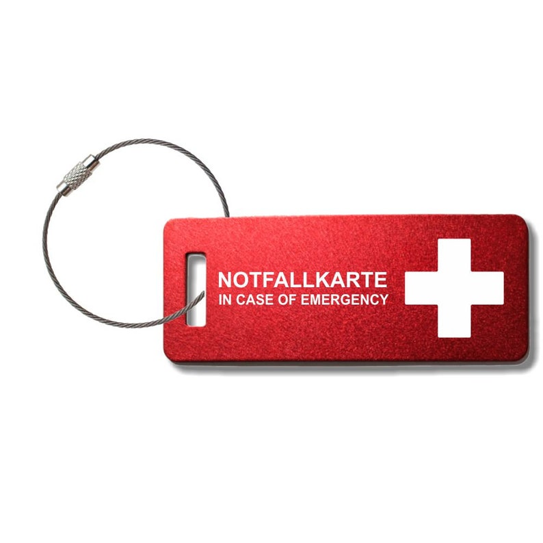 May include: Red metal emergency card with a white Swiss cross and the text "NOTFALLKARTE IN CASE OF EMERGENCY". The card is attached to a silver key ring.
