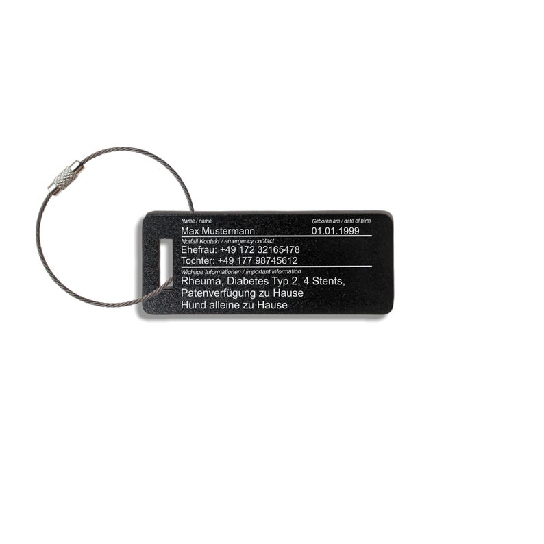 May include: Black metal tag with a silver cable loop. The tag has white text that reads "Name/name Max Mustermann Notfall Kontakt/emergency contact Ehefrau: +49 172 32165478 Tochter: +49 177 98745612 Geboren am/date of birth 01.01.1999 Wichtige Informationen/important information Rheuma, Diabetes Typ 2, 4 Stents, Patenverf&uuml;gung zu Hause Hund alleine zu Hause"