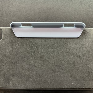 Peut inclure: Une housse pour iPad en feutre gris avec un support en plastique gris fixé sur le dessus. Le support comporte trois fentes pour maintenir l'iPad à différents angles.