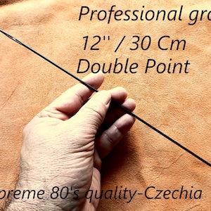 Puede incluir: Una aguja negra de doble punta, de 30 cm de largo, sostenida en una mano. El texto de la imagen dice "Professional grade" y "Supreme 80's quality-Czechia".