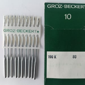 May include: A package of 10 silver sewing machine needles in a clear plastic case with the brand name "GROZ-BECKERT" printed on the case. The package is labeled "10" and "190 K 80".