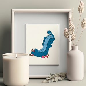 May include: A framed print of a blue caterpillar with a red and white striped hat, sitting on a mushroom. The caterpillar has a grumpy expression and is wearing a blue and white striped shirt.