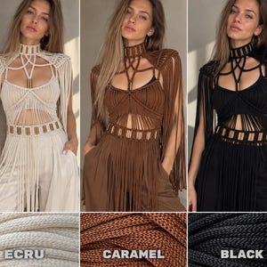 Op de afbeelding: Een macram&eacute; top met een hoge hals, ingewikkelde knoop patronen, lange franje mouwen en metalen cilindrische accenten bij de hals en taille. Het kledingstuk is verkrijgbaar in drie kleuren, aangeduid als Ecru, Karamel en Zwart.