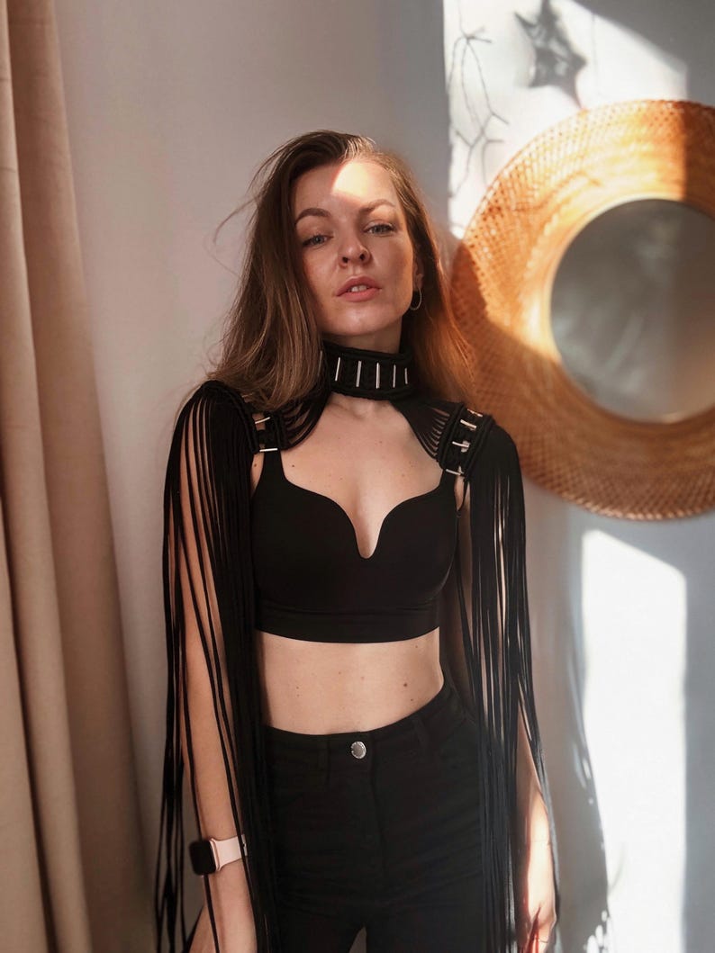 Peut inclure: Un haut noir court avec des d&eacute;tails en franges et un collier ras du cou noir avec des accents argent&eacute;s.