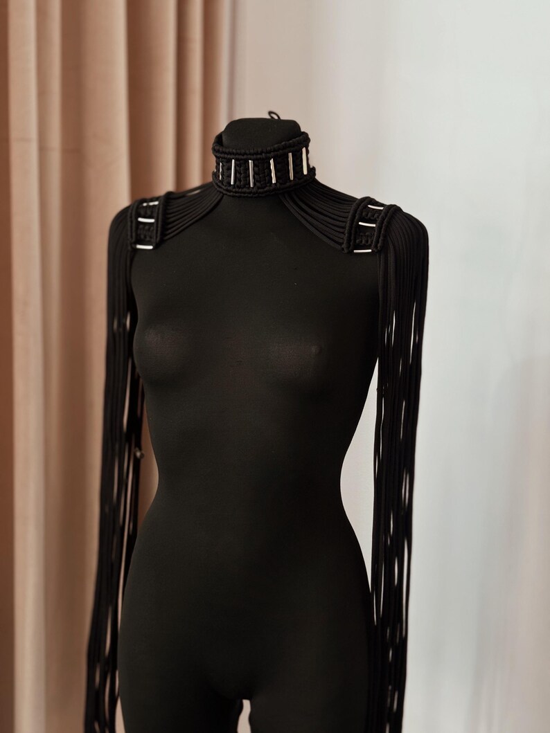 Peut inclure: Un collier ras de cou noir avec des accents argent&eacute;s et des bretelles assorties en cordon noir.