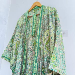 May include: A lightweight kimono-style robe featuring an intricate paisley pattern in shades of lime green, emerald, and soft peach. The garment has wide, three-quarter length sleeves, an open front design, and a matching fabric belt hanging down.