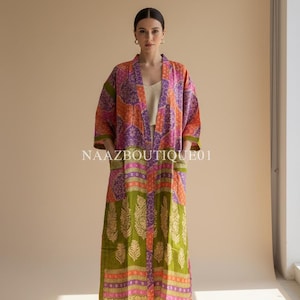 Könnte beinhalten: Langer, offen geschnittener Kimono-Stil-Bademantel mit Patchwork-Design in Orange-, Lila-, Rosa- und Grüntönen. Der Bademantel hat ein Blumen- und geometrisches Muster, mit dem Text "NAAZBOUTIQUE01" sichtbar. Das Kleidungsstück hat Taschen und Dreiviertelärmel.