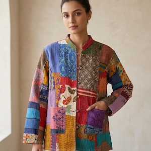 Könnte beinhalten: Eine bunte Patchwork-Jacke mit Stehkragen und langen Ärmeln. Die Jacke besteht aus verschiedenen Stoffflicken in Blau-, Rot-, Lila- und Brauntönen. Sie hat eine Knopfleiste und zwei Taschen.