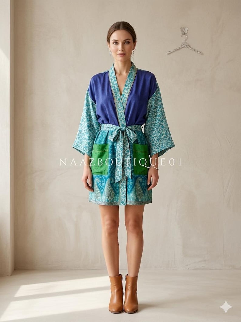 May include: A knee-length robe with a blue top and sleeves, and a green and blue patterned skirt. The robe has a matching belt and pockets. The text "NAAZ BOUTIQUE 01" is printed on the front of the robe.
