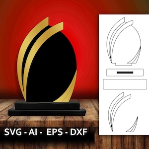 Może przedstawiać: Czarny i złoty puchar z zakrzywionym wzorem. Puchar ma podstawę i puste miejsce do grawerowania.