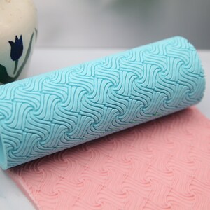 Può includere: Un mattarello blu e rosa con un motivo ondulato. Il mattarello è in silicone e viene utilizzato per decorare torte e pasticcini.