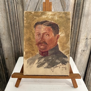 May include: An oil painting on canvas depicting a portrait of a person with a mustache, wearing a dark uniform with red collar details. The artwork features a muted olive-green background and includes the signature and the year 1918 in the corner.