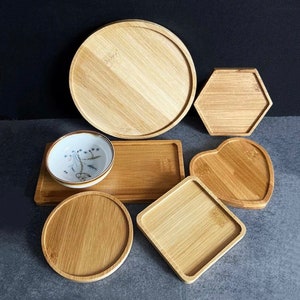 May include: Set of six wooden trays in various shapes, including round, square, heart, and hexagonal. The trays are made of natural bamboo and have a light brown color.