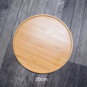 May include: A round, wooden serving tray made of bamboo. The tray is 20 inches in diameter and has a natural wood finish.