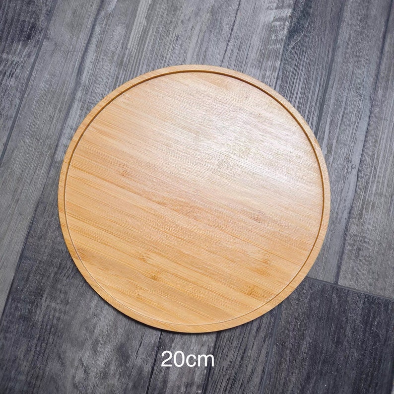 May include: A round, wooden serving tray made of bamboo. The tray is 20 inches in diameter and has a natural wood finish.